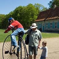 Toeristen bekijken oude fiets voor traditioneel woonhuis van Hoogstade in het openluchtmuseum Bokrijk, België
