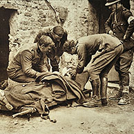 Aankomst van gewonde soldaat op brancard die onderzocht wordt door officieren en dokter in eerste hulppost in Vlaanderen tijdens de Eerste Wereldoorlog, België