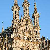 Toeristen op terrasjes voor het Gotische stadhuis op de Grote Markt van Leuven, België
